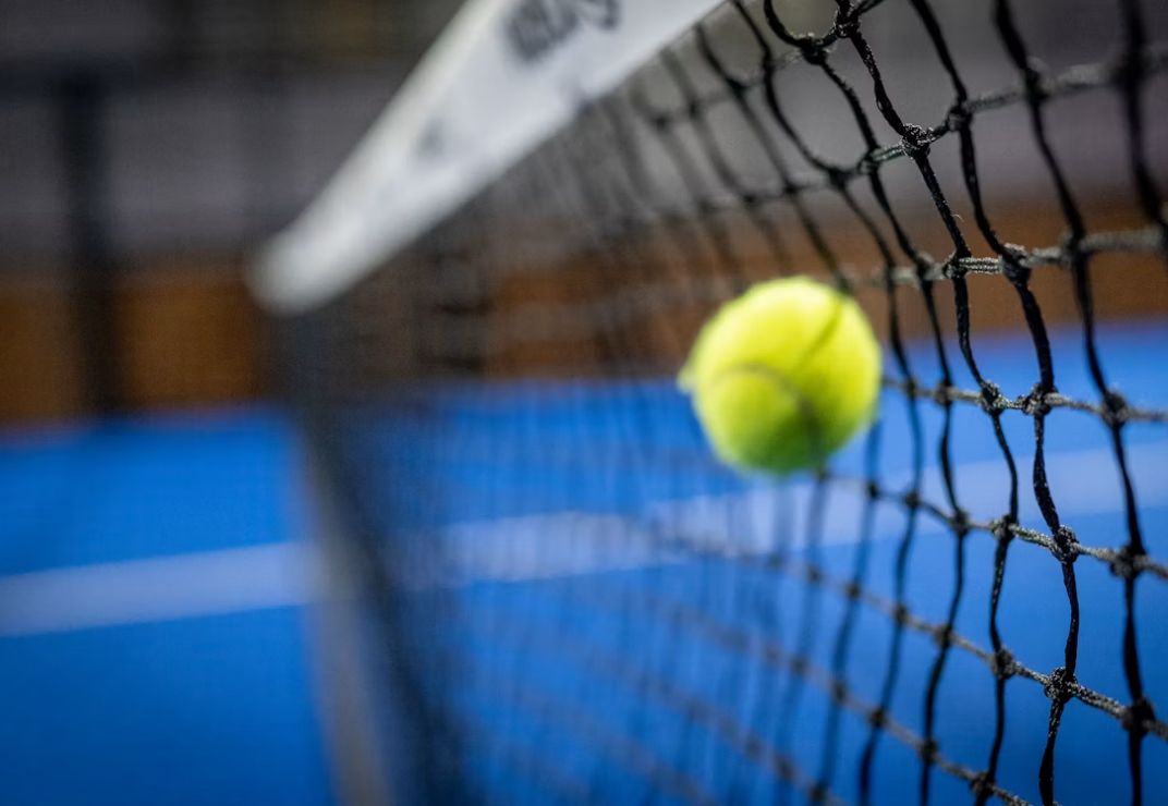 Pelota de pádel golpeando la red en plena jugada